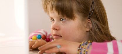 A close up of a child wearing colourful bracelets and typing on a laptop