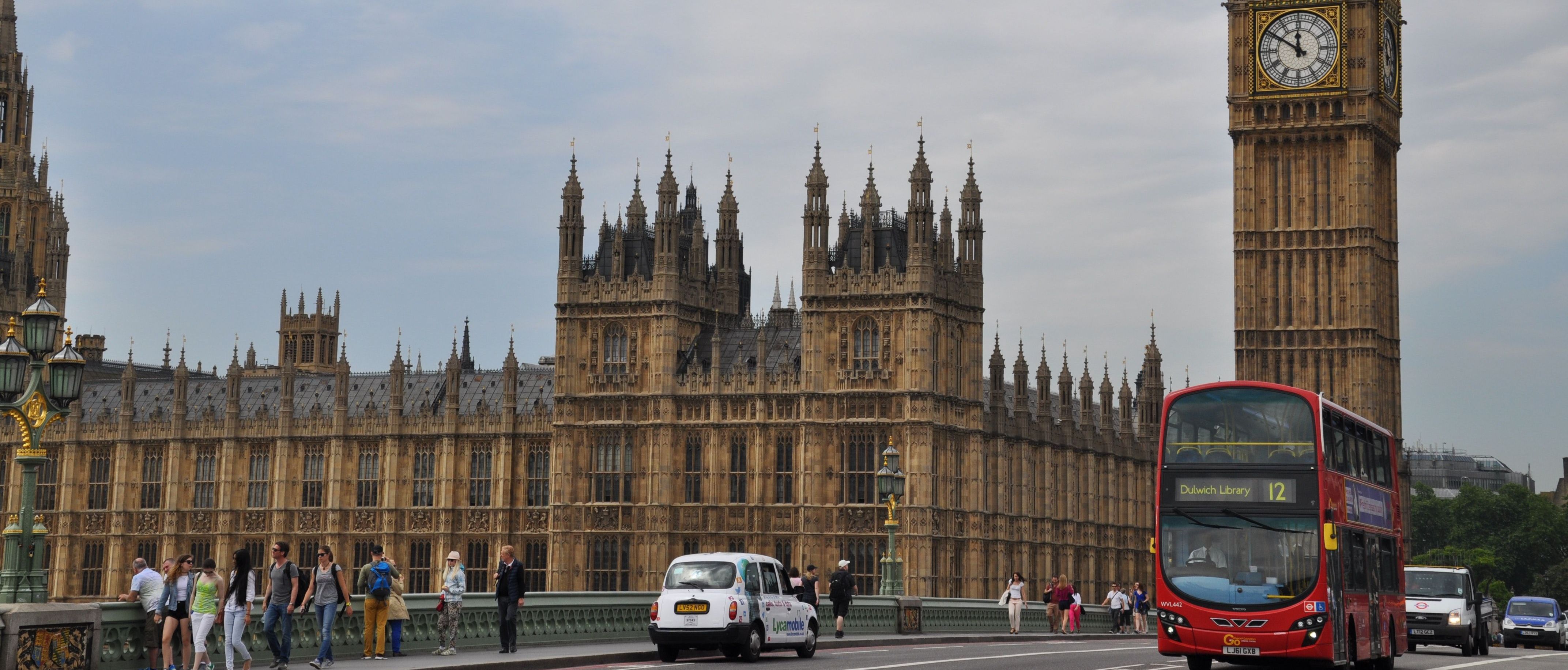 Houses of Parliament views from Westminster Bridge with a red double decker bus and cars on the road