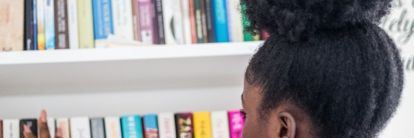 A young person with afro hair choosing a book from a shelf