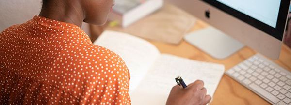 A person is writing in a notebook on a desk