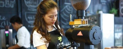  barista at work filtering coffee in front of a blackboard