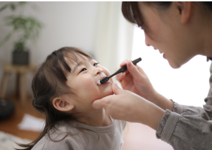 Adult brushes little girl's teeth 