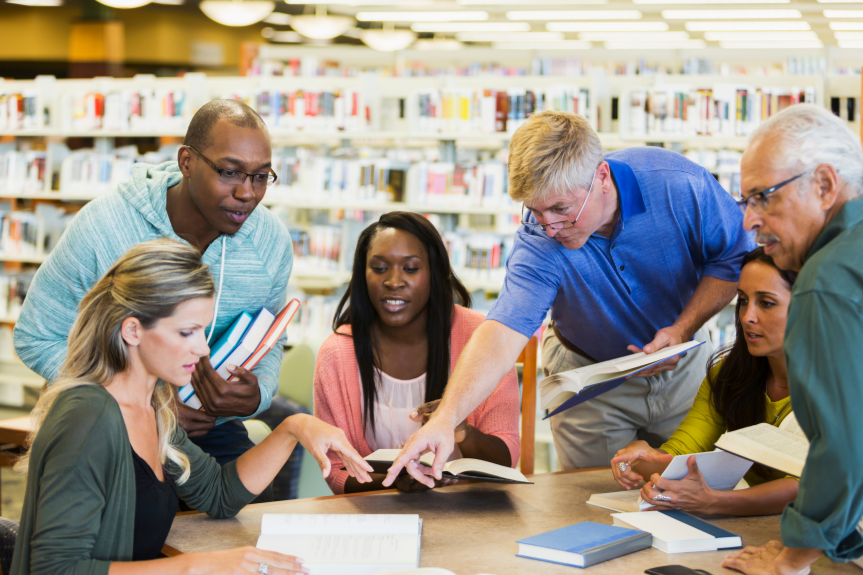 People gather around books and discuss in a library 